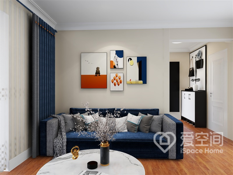 客厅空间简净通透，蓝色系沙发精致高雅，加以背景画的加持，空间充斥着艺术质感，彰显出设计美学。
