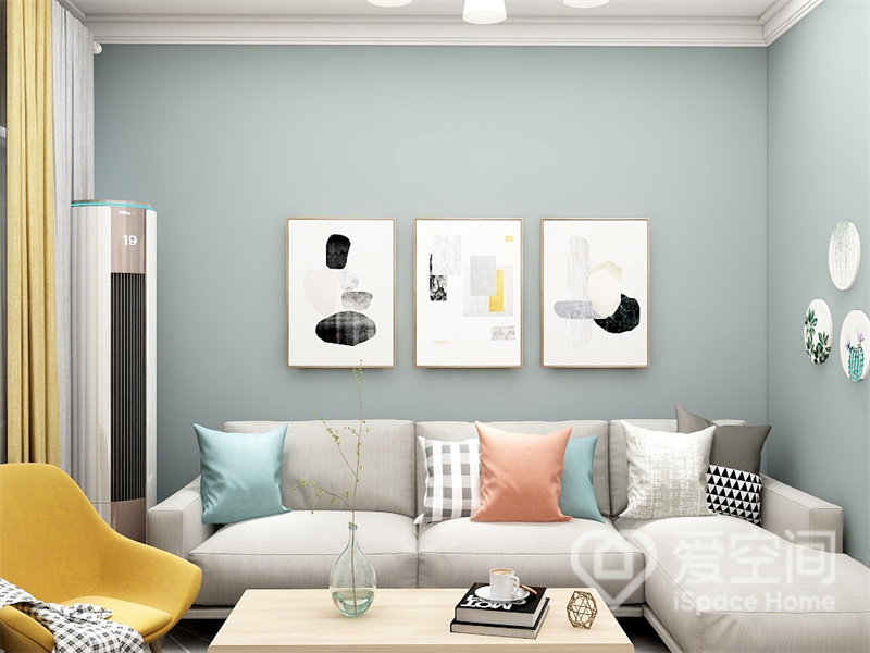 浅蓝色的背景墙，包裹着简约温馨的北欧家具，三幅装饰画形成视觉的延伸，暖色抱枕营造出温馨的客厅氛围。