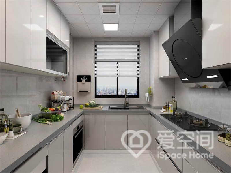 厨房空间中，灰色的台面干净简洁，米白色橱柜满足了厨房的收纳所需，呈现出冷静克制的烹饪氛围。