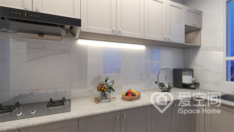 厨房吊柜与地柜的色调一致，中部铺贴了白色的操作台，在灯光的渲染下空间看上去更加柔和。