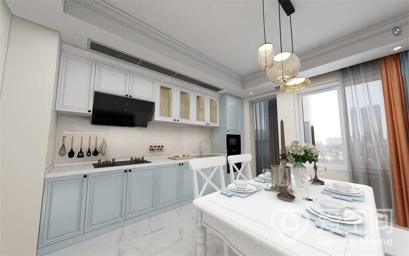 干凈整潔是餐廚空間給人的第一視覺感受，櫥柜一字型動線布置，藍色柜面與白色操作臺搭配，優雅的儀式感拉滿，白色餐桌椅為空間增加幾分活力與靈動感。