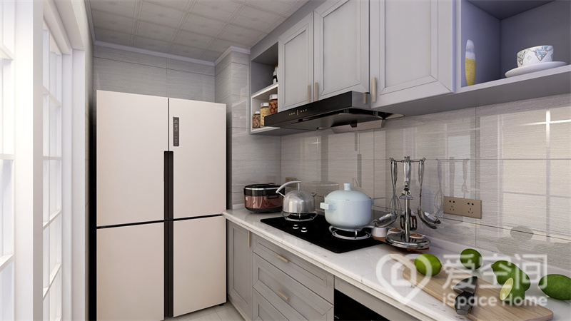厨房以简约风格为主，灰白色柜面令人感受到素雅温馨的氛围，冰箱填充了左侧空间，整体不显空旷。