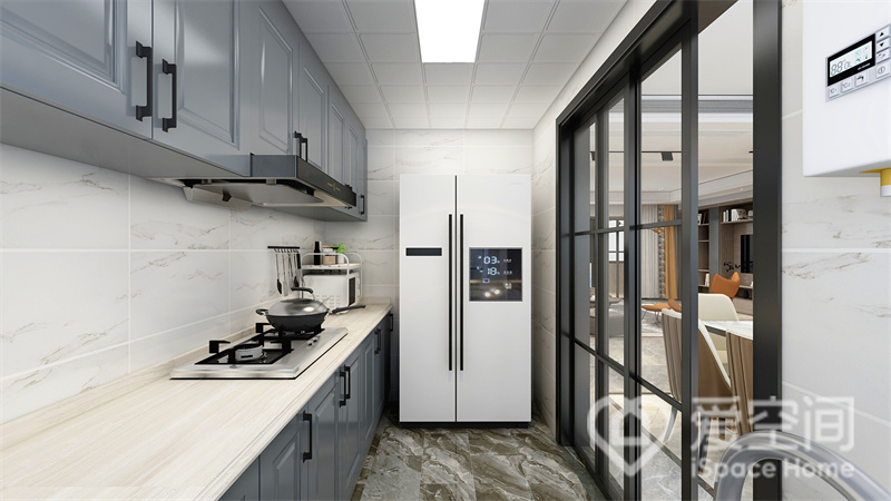一字型厨房，冰箱放端景位置，室内色彩层次丰富，不同材质之间的碰撞，打造出别致的厨房面貌。