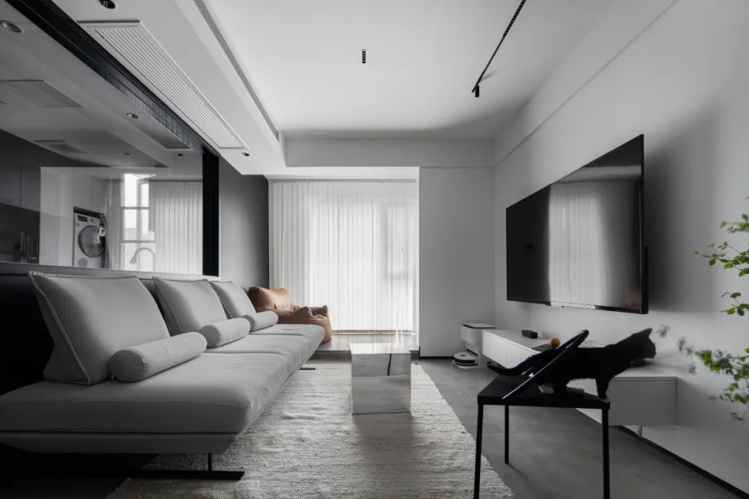 客厅以黑灰白为主色调，通铺浅灰色地砖，搭配沉稳朴素的家具，营造了一种舒适惬意的自然氛围，强化了空间层次感，让整体视觉效果更丰富。