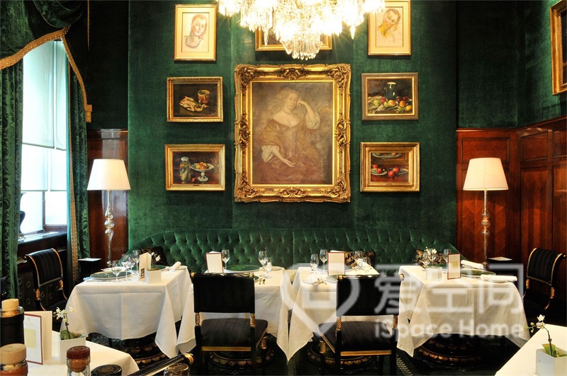 餐廳中，墨綠色背景與金屬畫框交相輝映，燈光照射下，閃爍出耀眼的光芒。