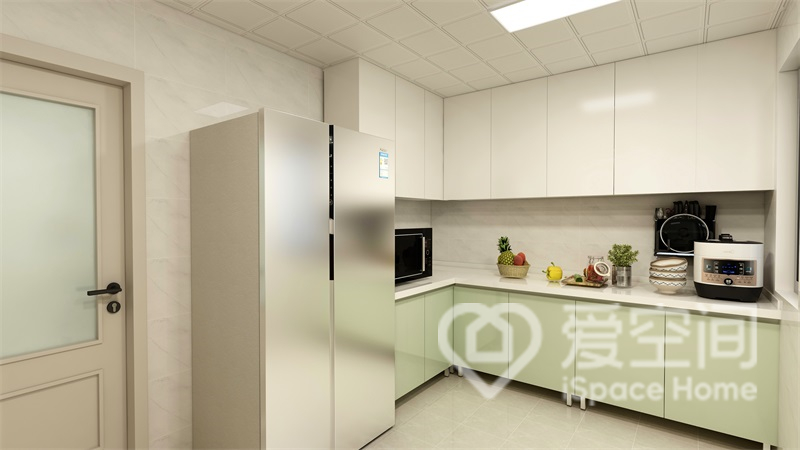 厨房使用白色和绿色橱柜分色打造，橱柜底部留出清理空间，方便日常清洁。