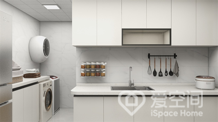 厨房呈现出干净的姿态，白色橱柜清爽色调，收纳架装点出时尚感，左侧过道放置了洗衣机，提升了空间的使用率。