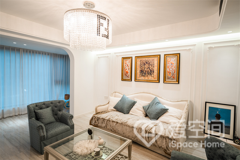 布艺沙发与背景墙融为一体，局部装饰画看起来颇具特色，在水晶灯的烘托下，呈现出简约而时尚的客厅氛围。