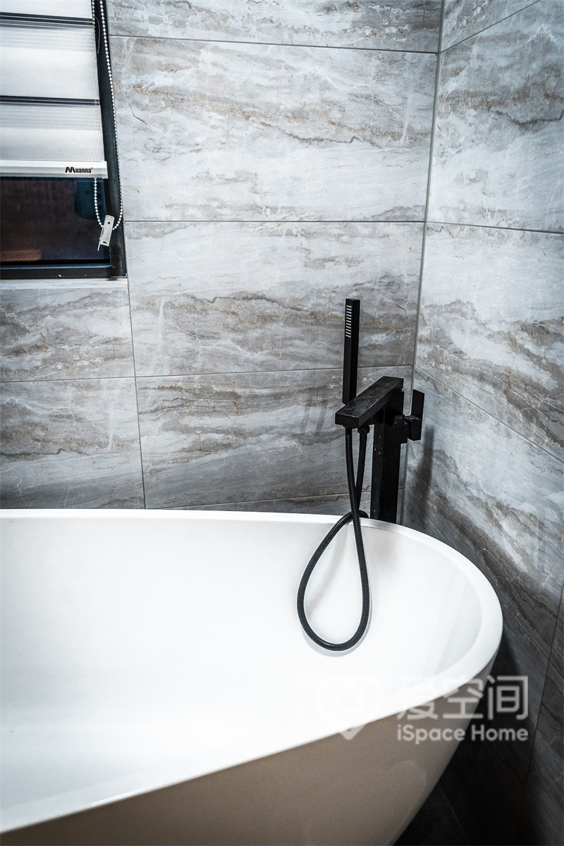卫生间中规划了浴缸设计，白色浴缸、黑色淋浴器和灰色背景，形成舒适的颜色层次，烘托出高级的都市质感。