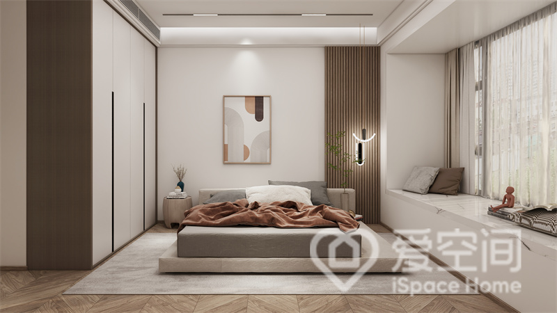主卧空间中，背景采用拼接式设计，一旁的灯具十分美观，灰色的低矮沙发看起来十分舒适。